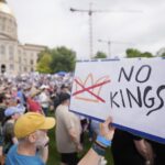 Crowds gather at “No Kings” protest rally in Washington, D.C., holding signs opposing President Trump.