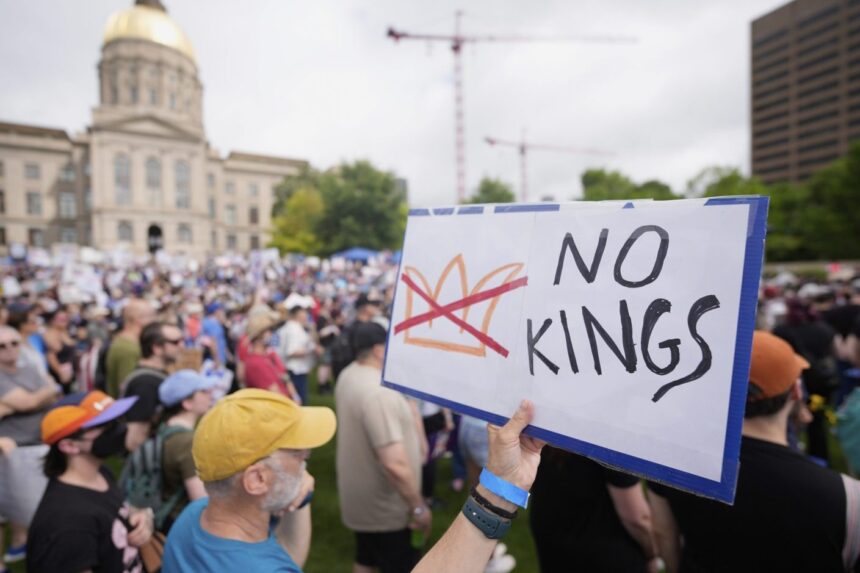 Crowds gather at “No Kings” protest rally in Washington, D.C., holding signs opposing President Trump.